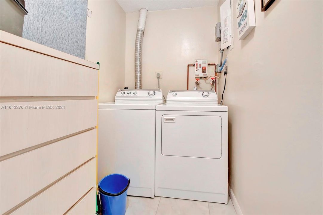 Large dedicated laundry room has storage and full-size washer and dryer