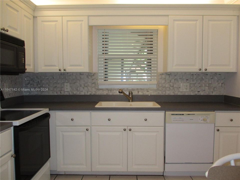 WHITE UPGRADES CABINETS, DOUBLE SINK WITH A WINDOW FOR NATURAL LIGHT