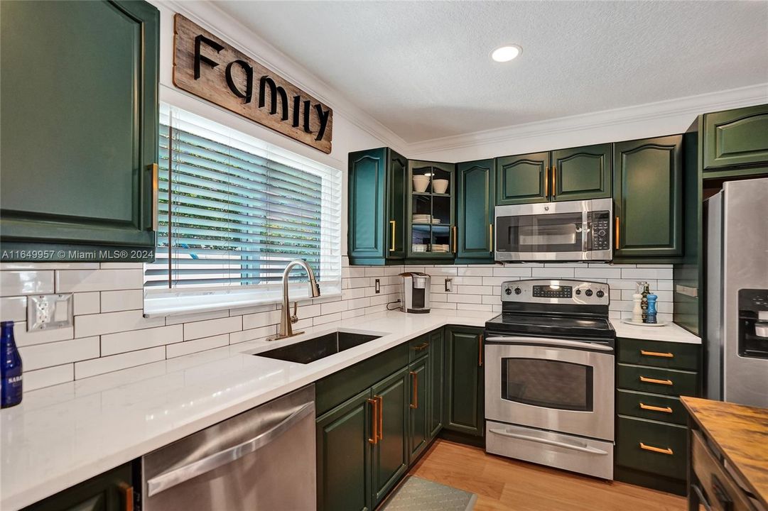 Elegant white subway tile complements the sleek stainless steel appliances and stunning brass hardware.