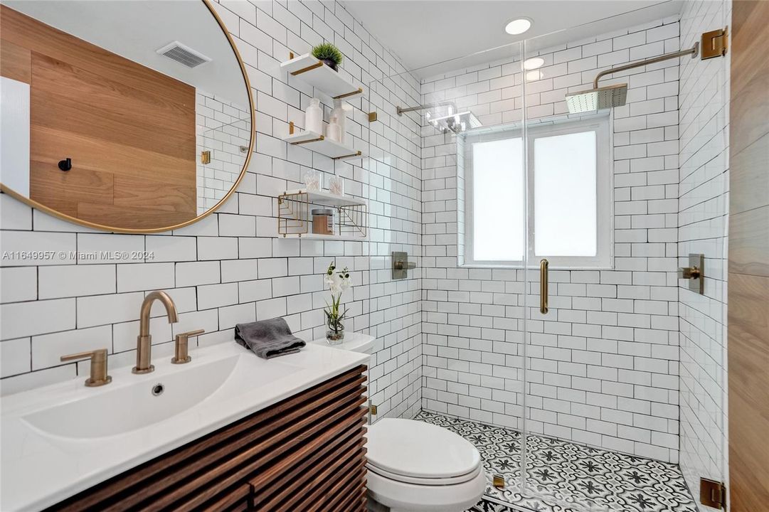 Beautifully renovated, primary bathroom with designer shower, elegant white subway tile and dual shower heads, combining style with functionality.