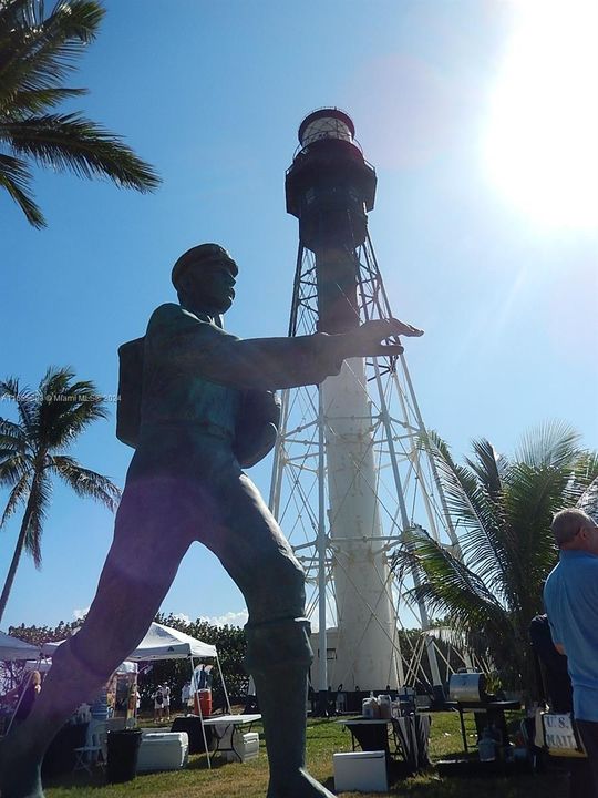 Legendary Barefoot Mailman statue in shadow of Hillsboro Inlet Lighthouse