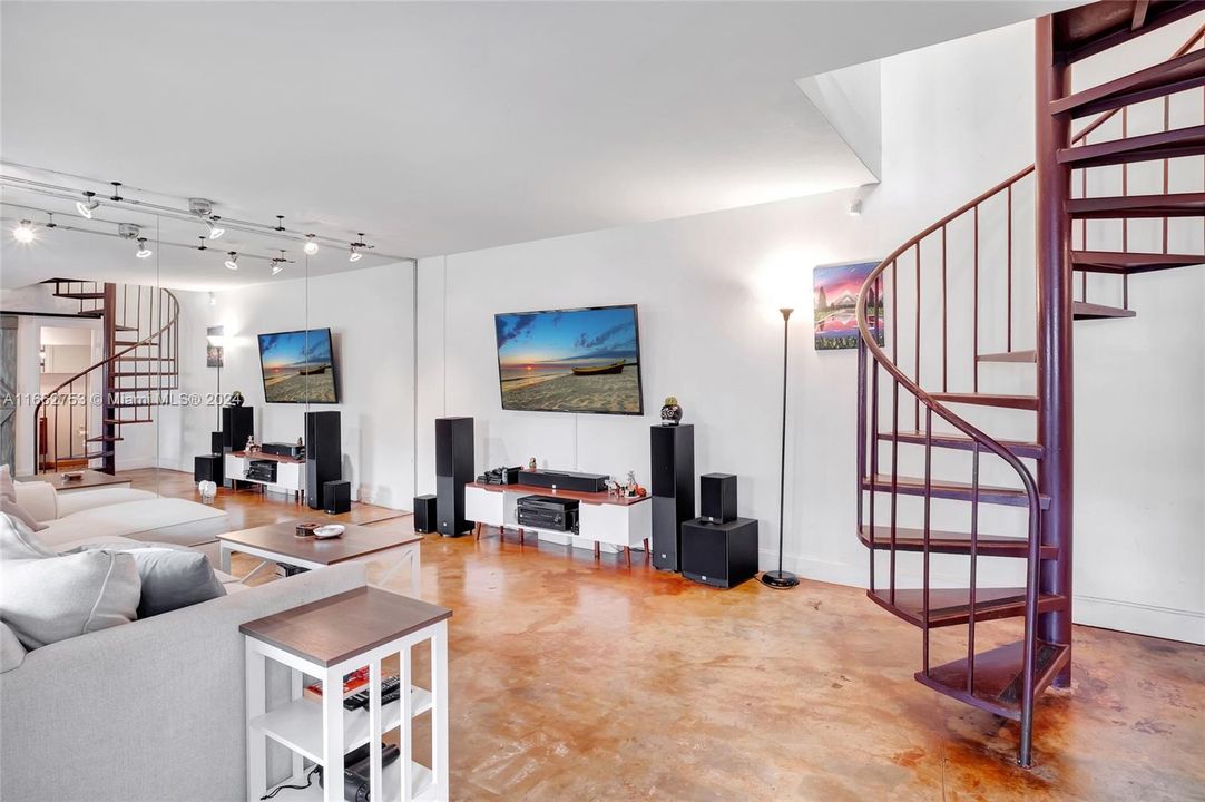 Open floor plan with spiral staircase and stained concrete floor give the home an edgy, uptown vibe!