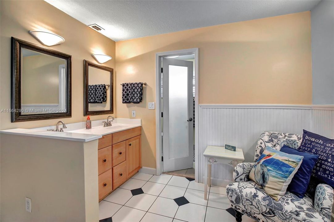 Wow, dual sinks, a sitting area, and glass bathroom door.