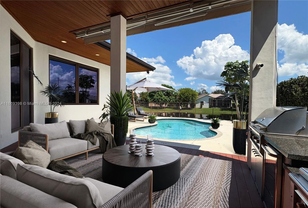 Outdoor kitchen with grill, gridle, gas burners, and mini fridge. Brazilian ipé hardwood decking.Hardwood tongue-and-groove cladding in patio ceiling. Motorized retractable sun shades.