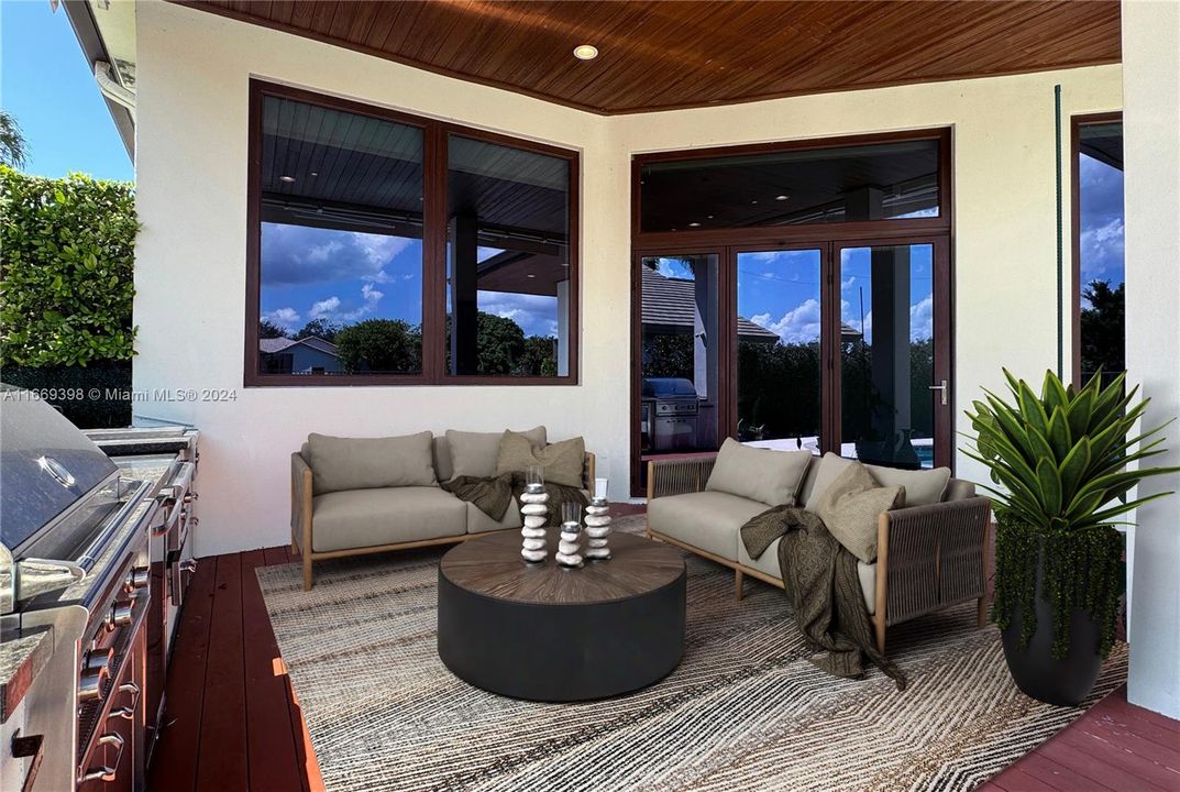 Outdoor kitchen with grill, gridle, gas burners, and mini fridge. Brazilian ipé hardwood decking.Hardwood tongue-and-groove cladding in patio ceiling. Motorized retractable sun shades.