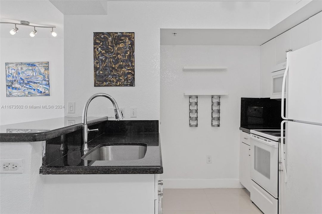 Looking into kitchen. Modern faucet w granite counter.