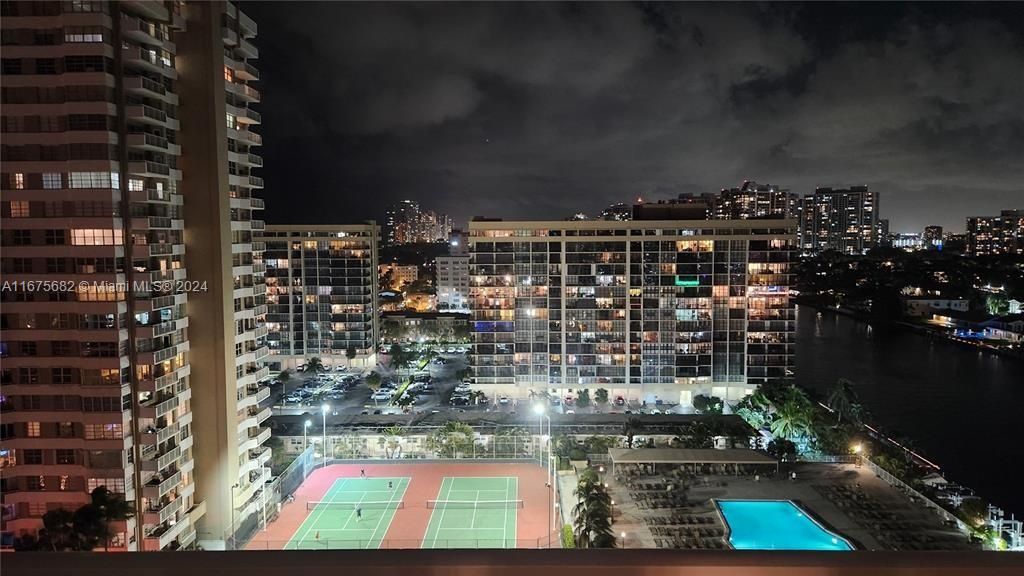 lighted tennis courts and bayside pool area lights up with boats going by