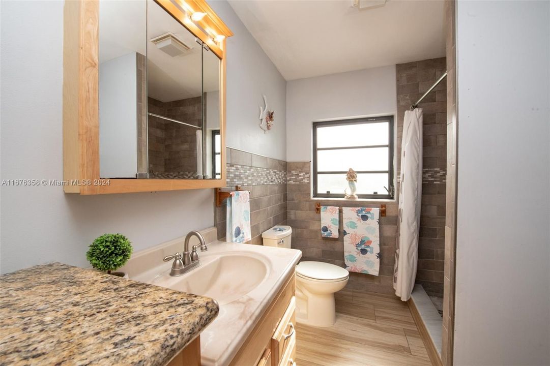 The bathroom has shower and cabinents have granite countertop.