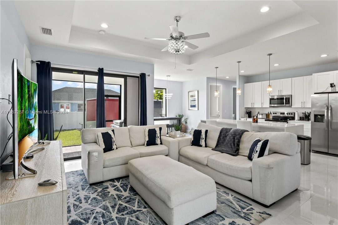 Living room with ceiling fan and a tray ceiling