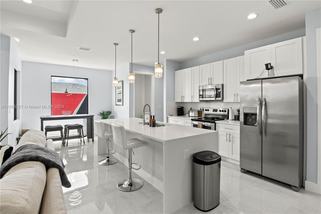 Kitchen with an island with sink, appliances with stainless steel finishes, sink, and white cabinetry