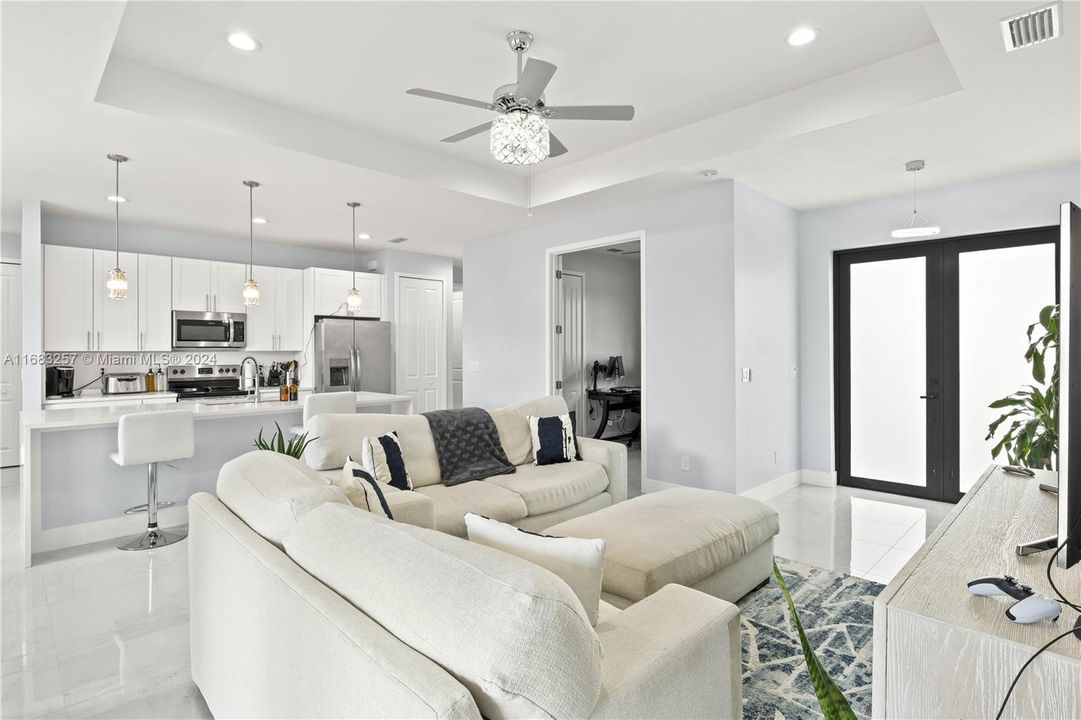 Living room with ceiling fan, french doors, and a raised ceiling