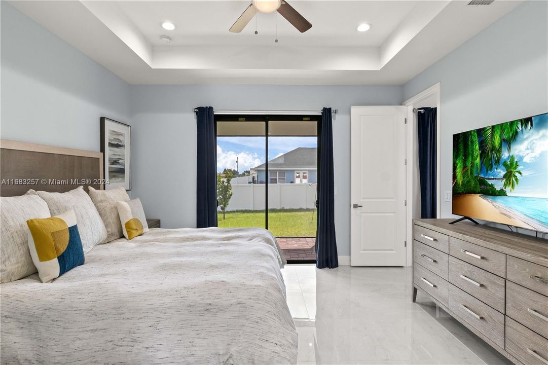 Bedroom featuring access to outside, a raised ceiling, and ceiling fan