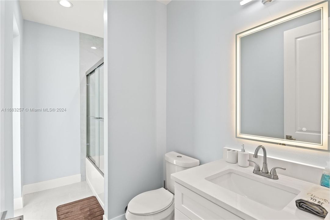 Full bathroom with tile patterned floors, shower / bath combination with glass door, vanity, and toilet