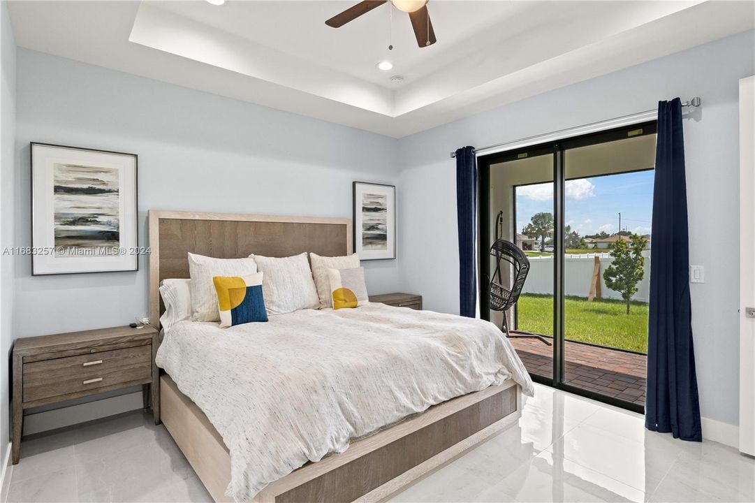 Bedroom featuring access to exterior, ceiling fan, and a raised ceiling