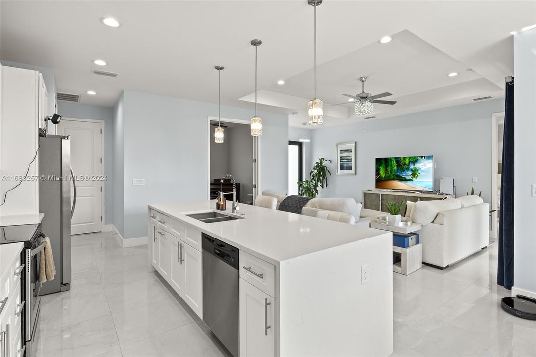 Kitchen featuring decorative light fixtures, sink, an island with sink, appliances with stainless steel finishes, and white cabinetry