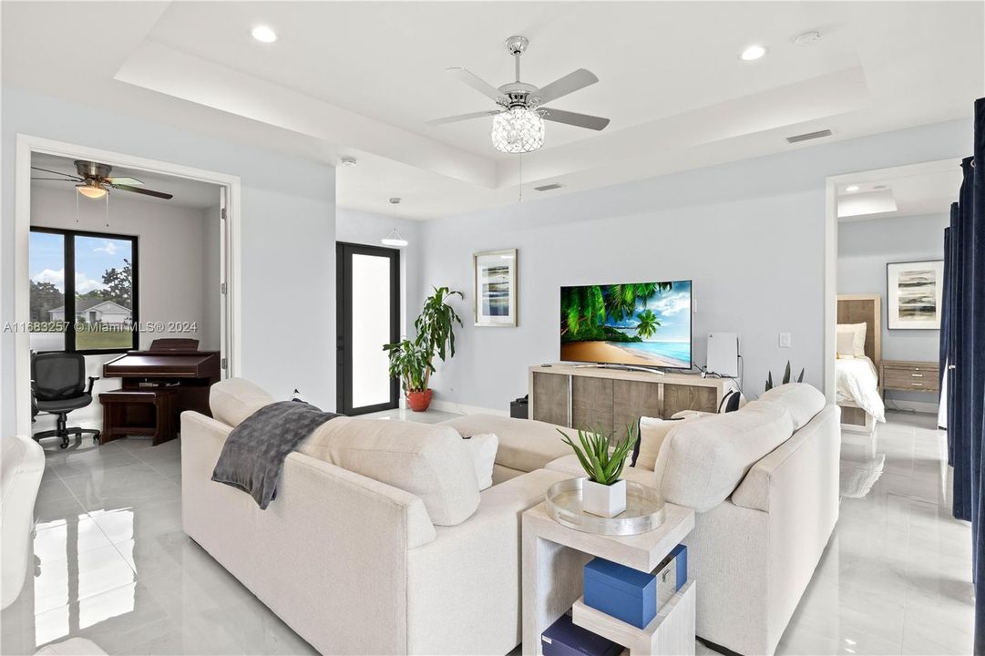 Living room featuring ceiling fan and a raised ceiling