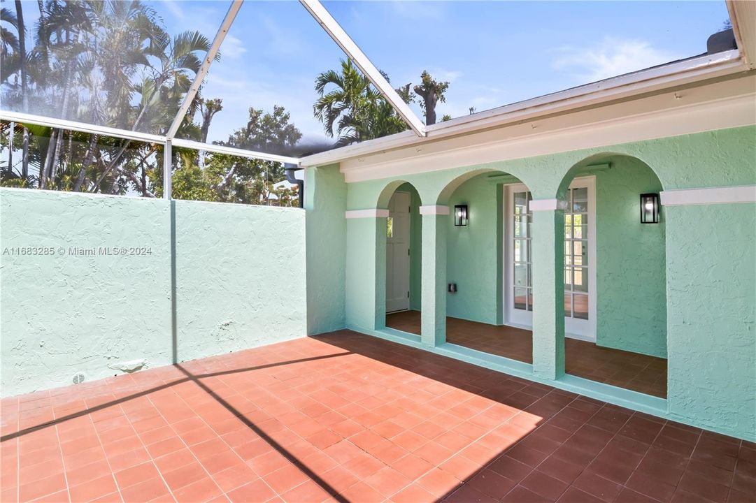 View of the courtyard looking towards the guest quarters with double french door and a covered walkway to the main home.