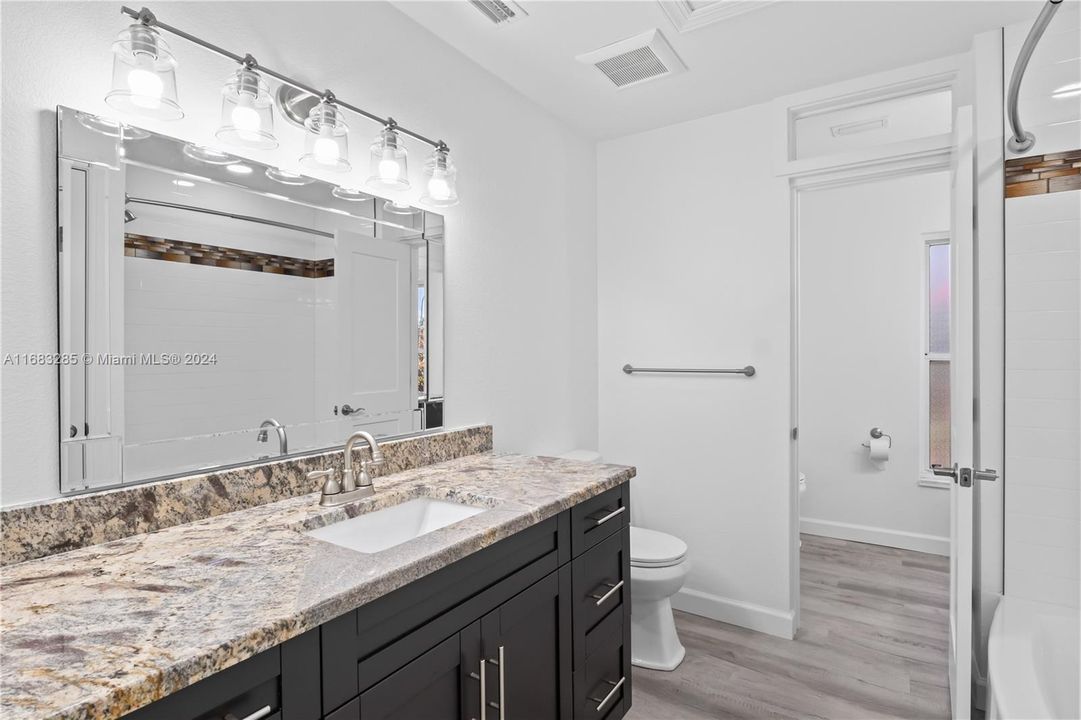 Bath and shower combo with accented tile, custom vanity with granite counter top.