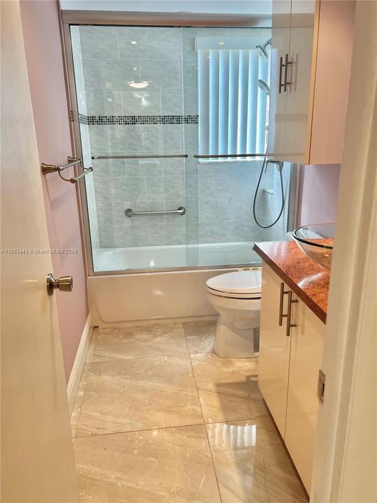 Updated guest bathroom featuring large modern floor tile and shower grab bar.