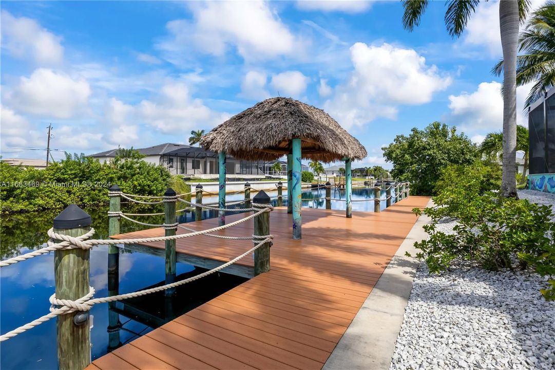 View of dock featuring a water view - so many additional features in this home including beautiful painted artwork on back wall and tiki poles from a local artist!