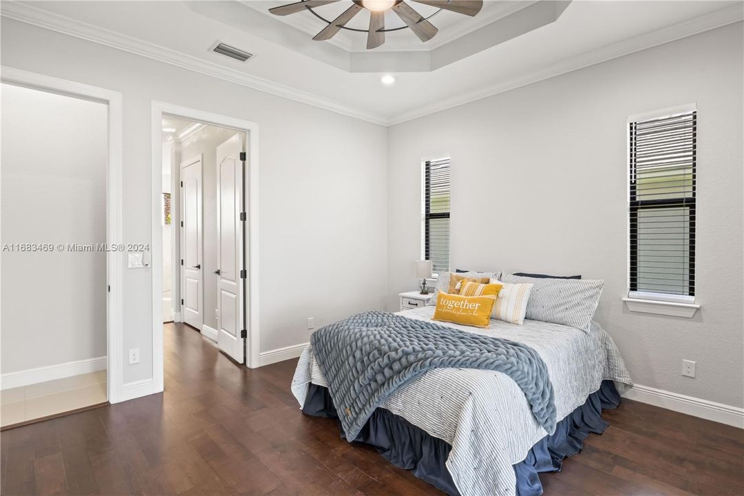 Primary bedroom with door to master bathroom. Beautiful neutral paint palette throughout the home and those floors are just gorgeous!