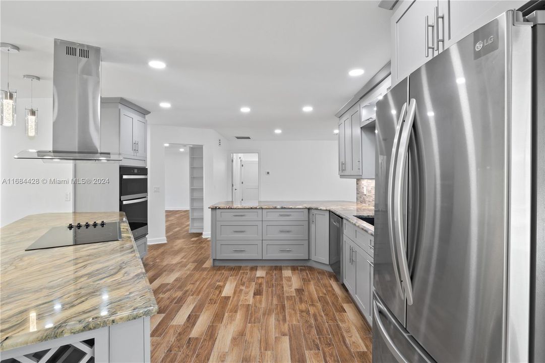 Bright, open-concept kitchen with integrated dining space, large windows, and contemporary lighting, creating a welcoming atmosphere.