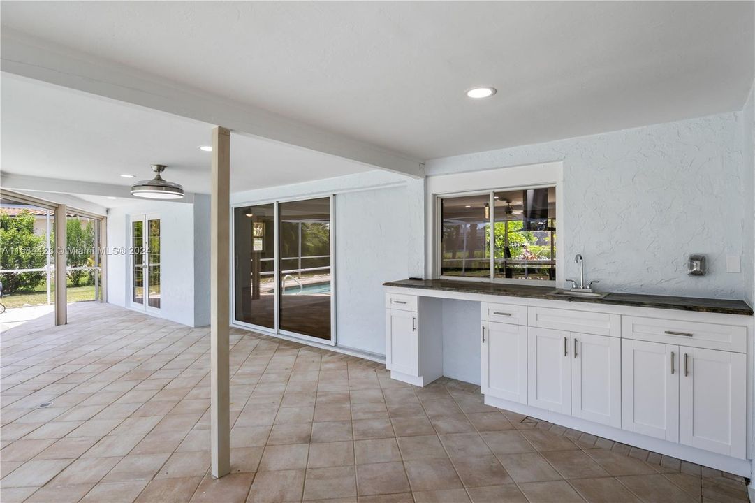 The outside patio is as expansive as the indoors! A pass thru window from the kitchen leads to a buffet counter with sink. Perfect for entertaining and lots of shade. Bonus - Kevlar remote screens for an additional layer of hurricane protection.