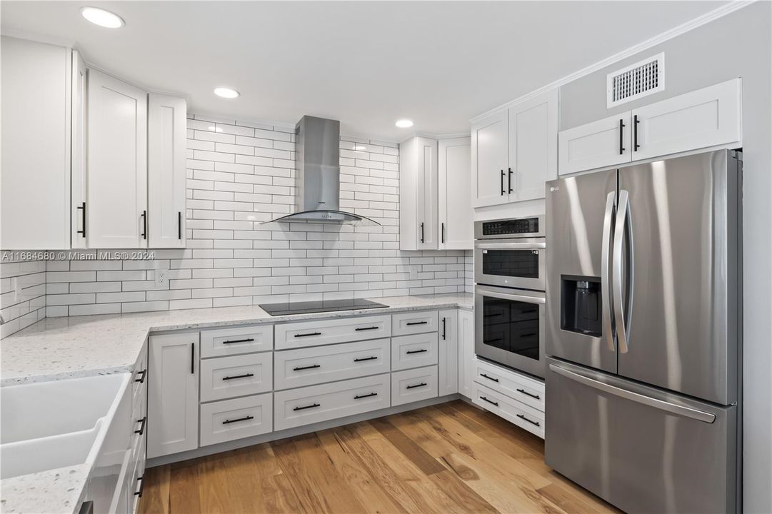 Sprawling kitchen with farmhouse sink, pull out cabinetry, a subway tile backdrop and upgraded stainless steel appliances!