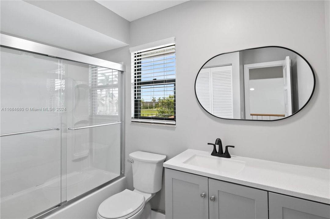 Second floor full bathroom with combined bath / shower with glass door, toilet, and vanity