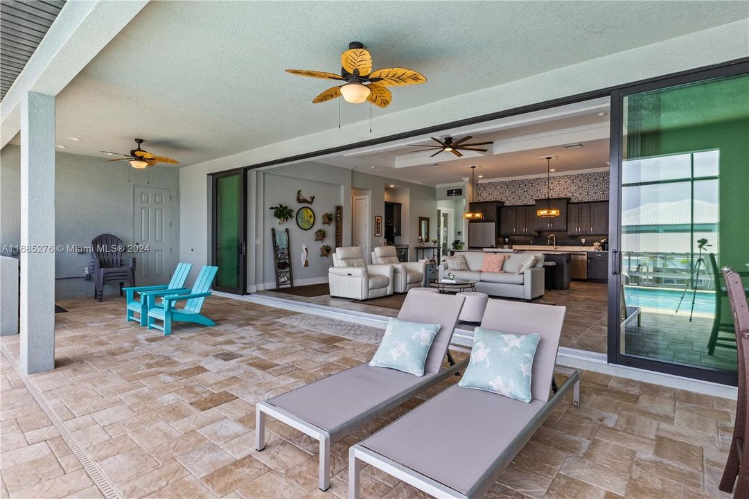 View of patio featuring outdoor lounge area and multiple ceiling fans! Slider doors are hurricane impact and disappear for that wide open extension of living areas! With access to the pool bath and pre-plumbed for an outdoor kitchen!