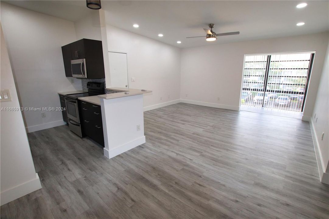 View from the dining area with kitchen on left and enclosed balcony opening in front