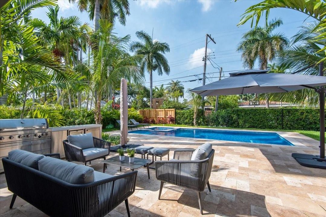 Pool area features a built-in outdoor kitchen with a refrigerator