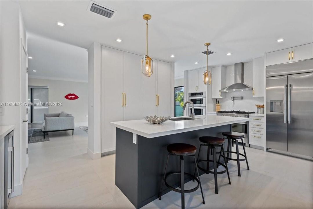 Sleek, modern kitchen featuring a large center island with bar seating, custom cabinetry, and elegant pendant lighting.