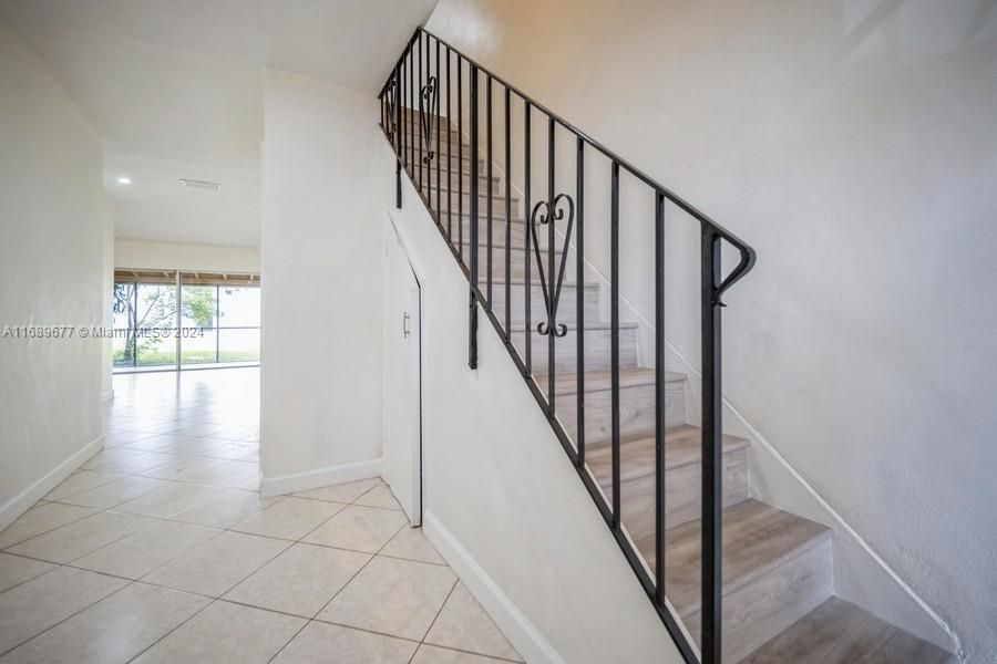 From the front door entry/foyer you can see out thru the Familyroom sliding glass doors to see thru the patio and to grass beyond! Notice the door under the staircase that has ample storage for things all year. The staircase has new laminated wood floors leading to the 3 Bedrooms upstairs.