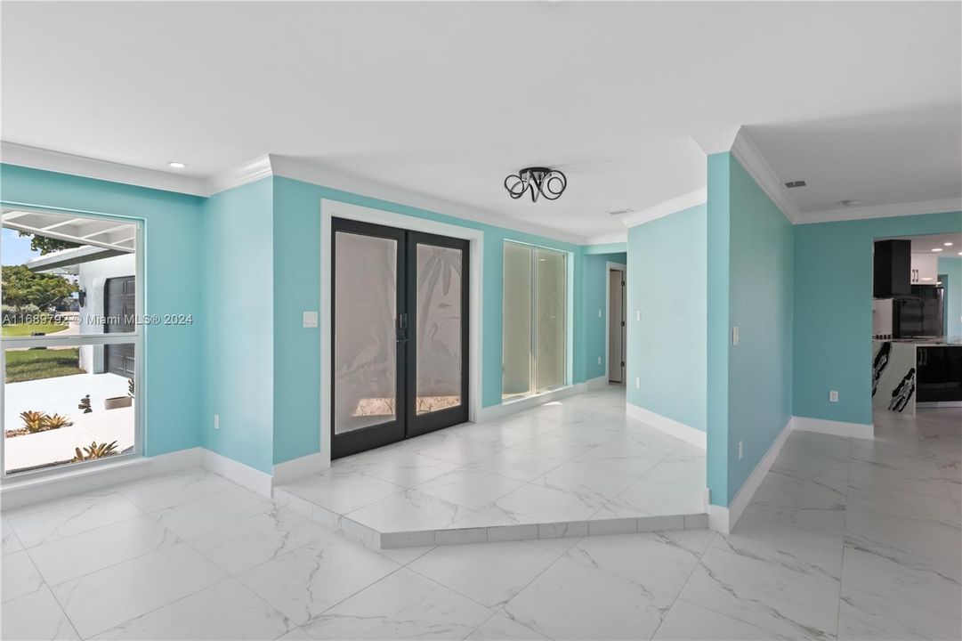 Empty room featuring crown molding, french doors, and tile patterned floors