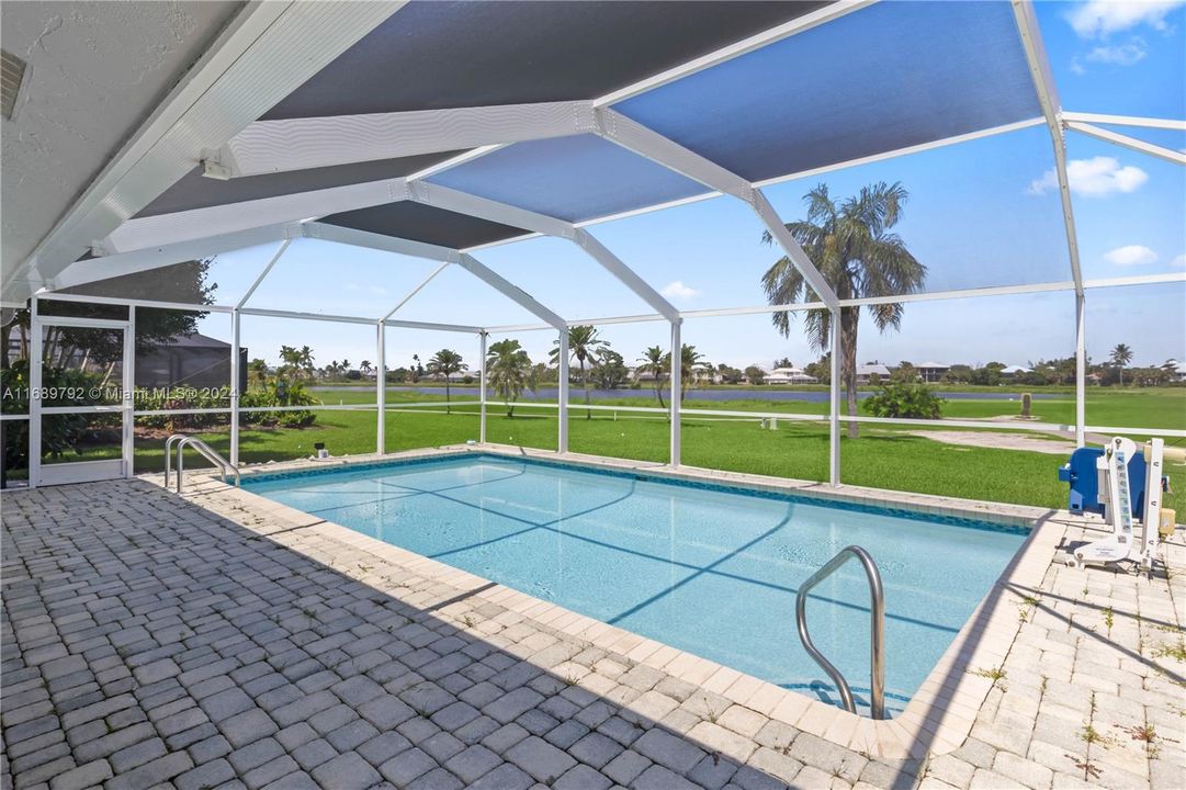 View of swimming pool with a lawn, glass enclosure, and a patio with golf views!