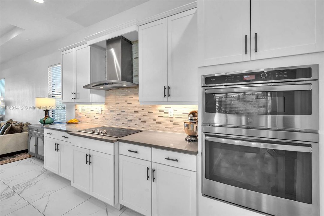 Notice High End SS Appliances, Backsplash & White Cabinetry