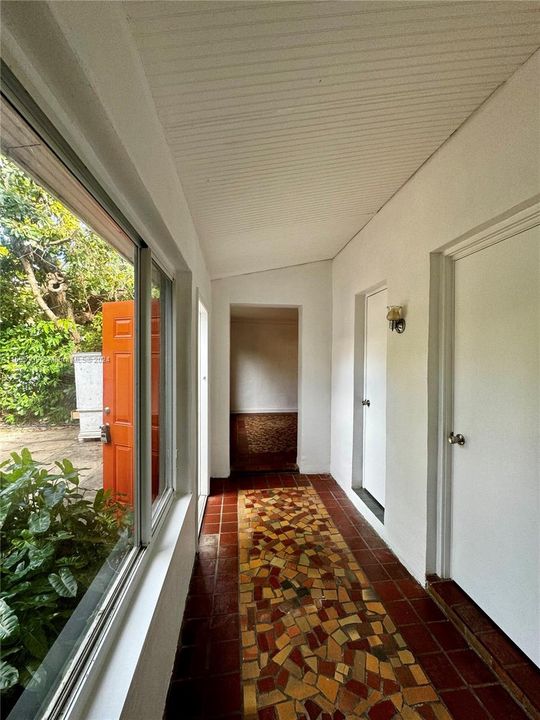 The picture shows a corridor leading straight to the living room, with side doors providing access to the bedroom and bathroom.