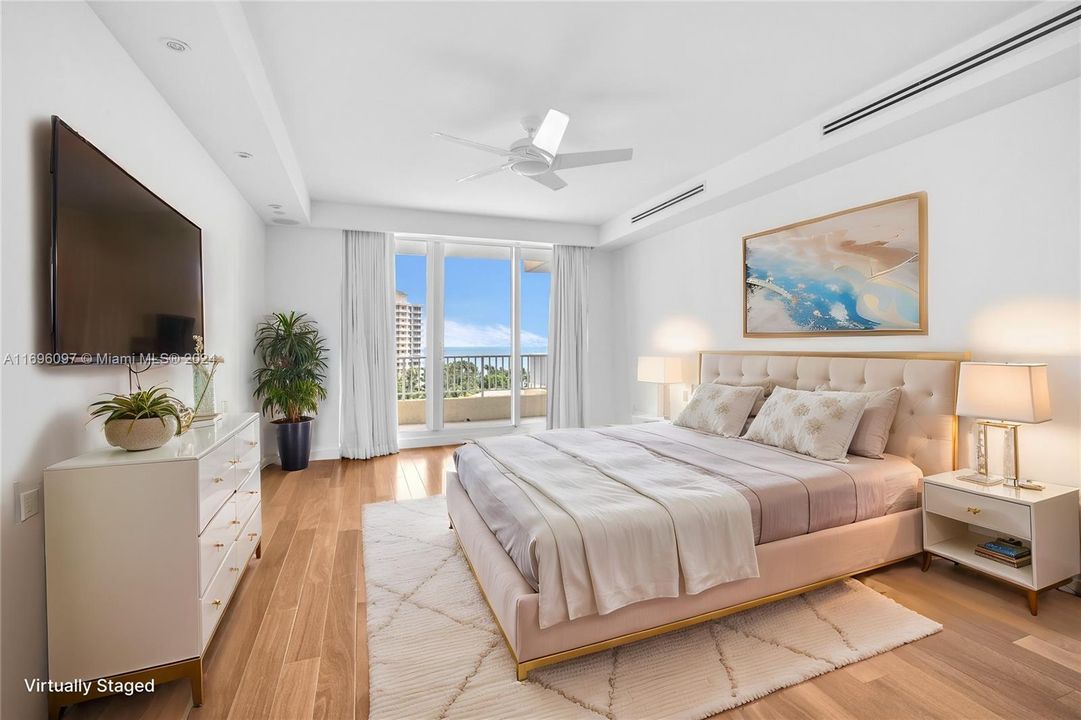 Bedroom with wood floors, access to the balcony, and ocean views.