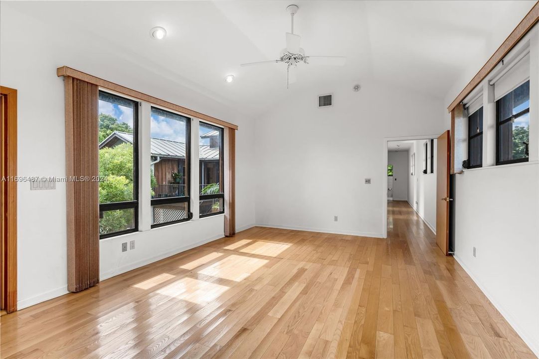 LIVING ROOM SHOWING THE HALLWAY ADORNED WITH WINDOWS TO THE BEDROOMS.