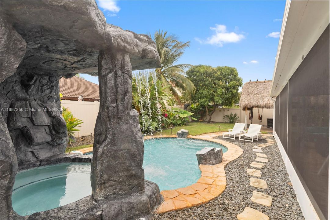 heated pool and hot tub. with waterfall grotto, tiki covered outdoor kitchen and Firepit area