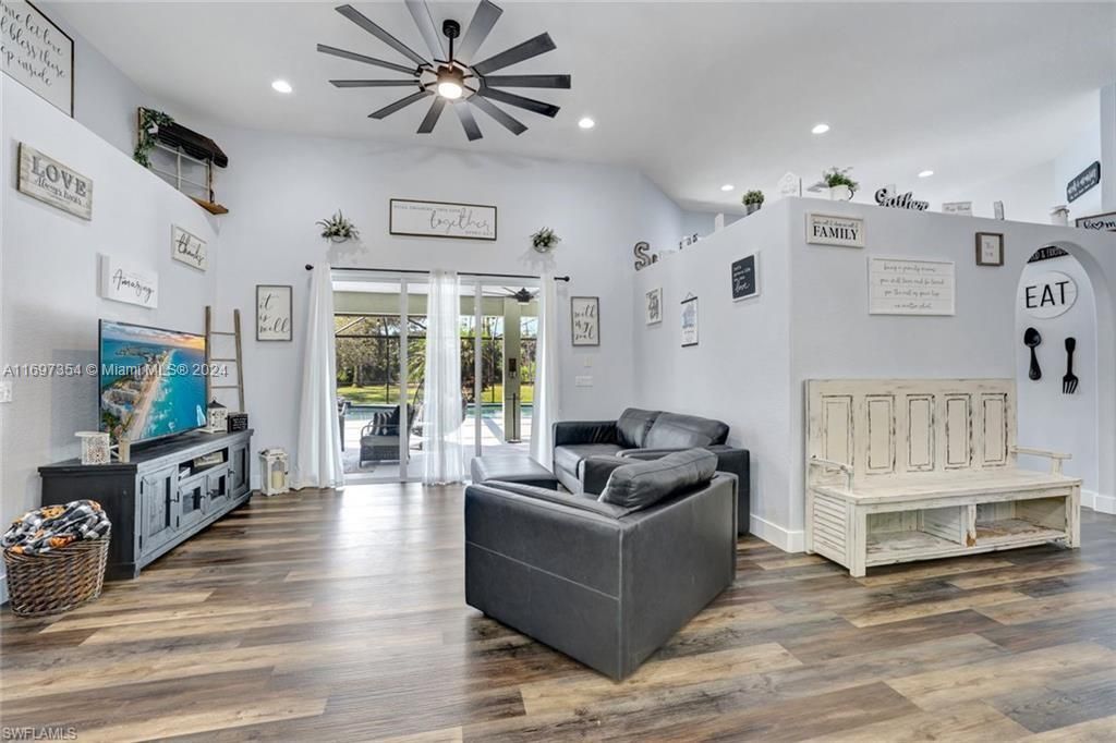 Living room with dark wood-type flooring, high vaulted ceiling, and ceiling fan