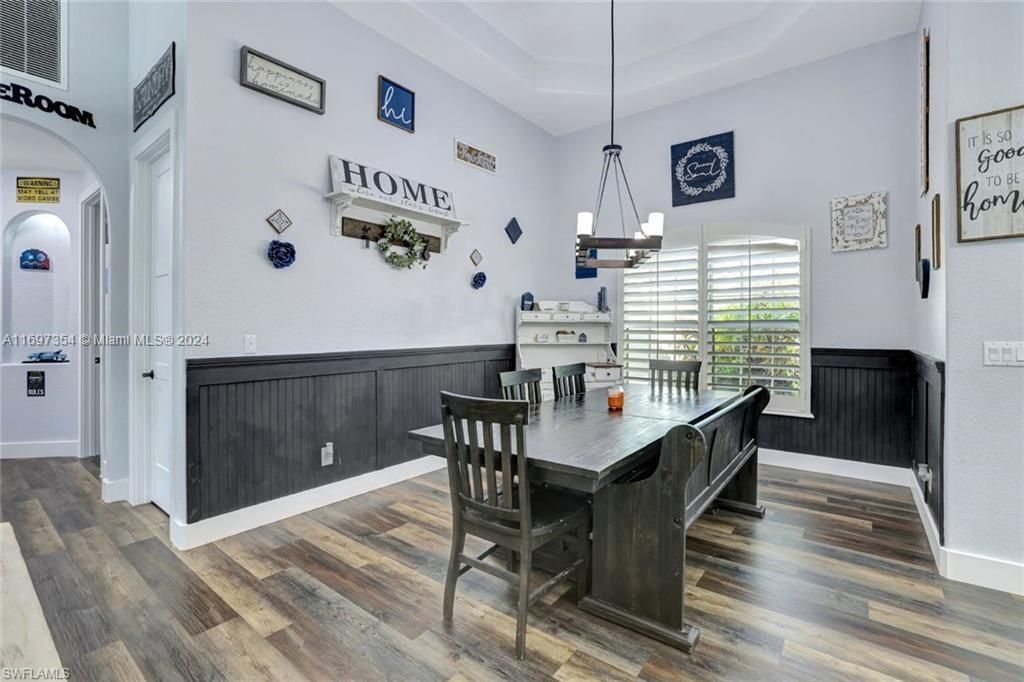 Dining area featuring a notable chandelier, a tray ceiling, a high ceiling, and dark hardwood / wood-style flooring