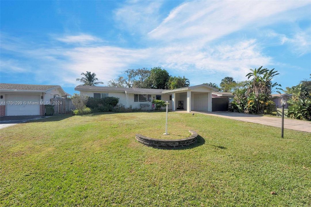 Front yard and long driveway leading into carport