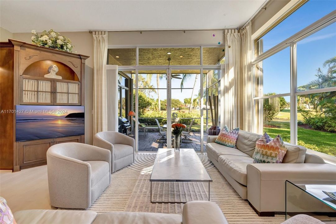 Bright living room w/ Hunter Douglas honeycomb window treatments on the side. Custom built in for display of art. Volume Ceilings.