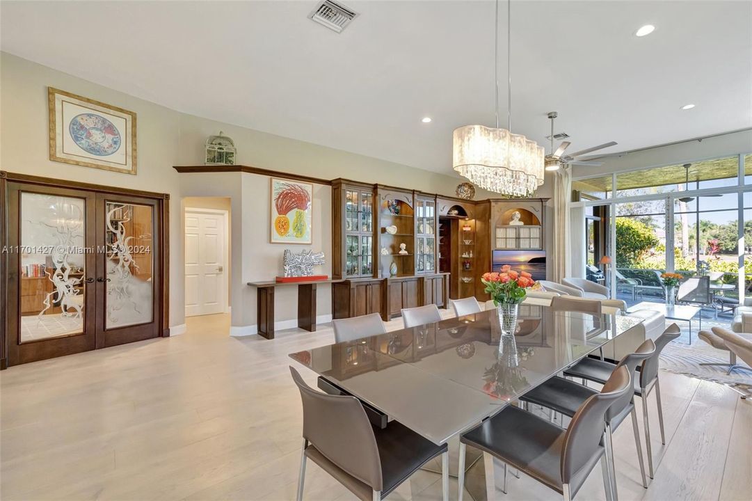 Bright dining / living room combo w/ Hunter Douglas honeycomb window treatments on the side. Custom built in for display of art. Volume Ceilings. View to Guest Bathroom down hallway, and double doors lead to 3rd bedroom (currently being used as an office)