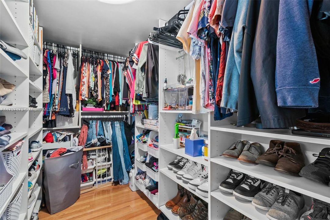 Primary closet featuring custom closet cabinetry