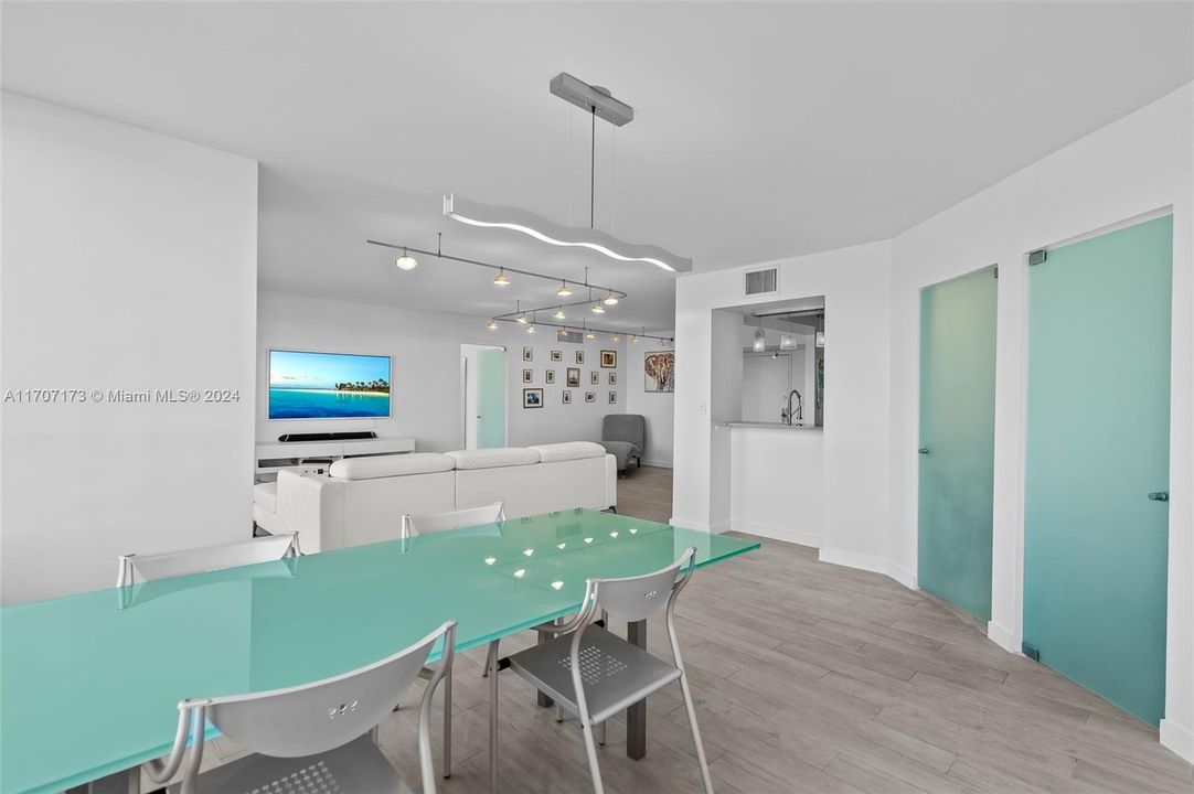 Dining area with view to living area, guest room and bath in background with doors shut.