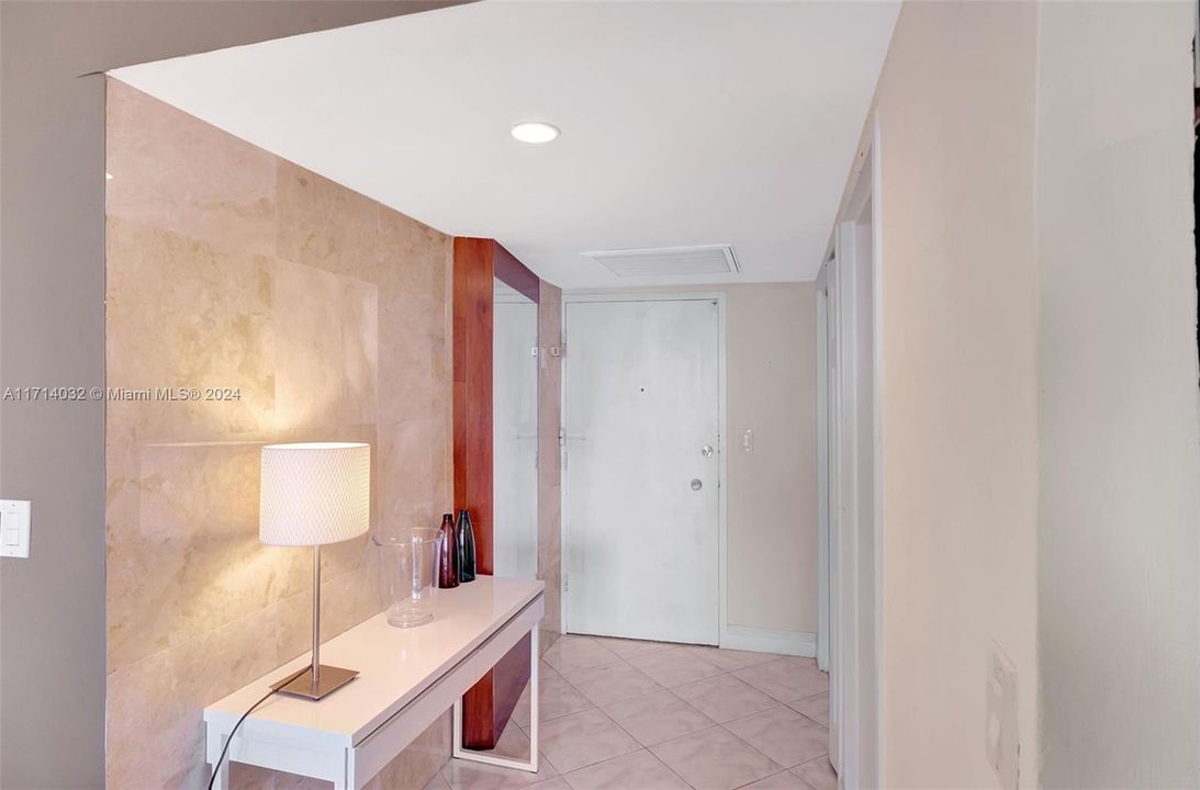 Foyer entry with custom mirror, marble wall and large closet.