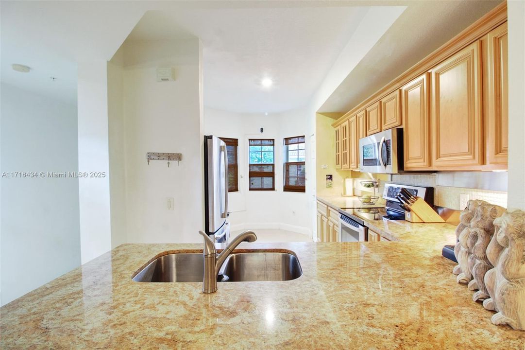 Kitchen features lots of granite countertops and lots of cabinets for storage.